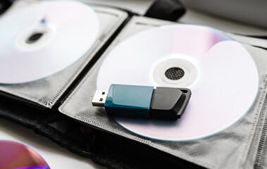 Bunch of CD and DVD discs with USB flash drive placed on them.
