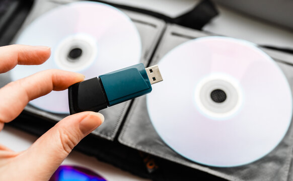 Bunch of CD and DVD discs with USB flash drive placed on them.