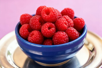 A vibrant still life featuring a bowl brimming with ripe raspberries, perfect for health or dessert related designs. This image evokes freshness and natural goodness.