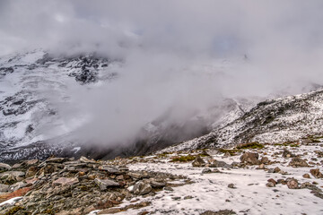 A mountain range covered in snow and clouds. The sky is overcast and the mountains are covered in snow