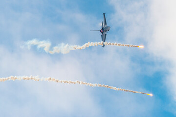 Wojskowy odrzutowy samolot myśliwski wystrzeliwujący flary podczas pokazów lotniczych © piotr