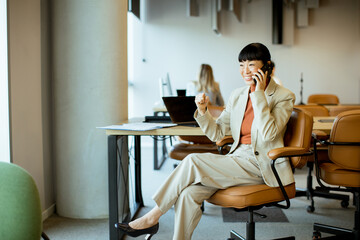 Businesswoman in a modern office celebrating a successful phone call