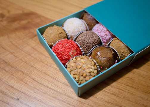 Detalhe de doces artesanais numa caixa personalizados em cima de mesa de madeira. 