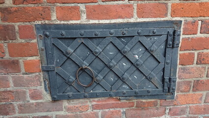 Old metal hatch in brick wall