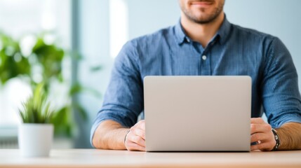 Person Working on Laptop in Bright Office Space Surrounded by Greenery