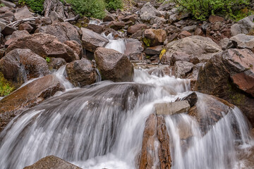 A stream of water flows over a rocky bed. The water is clear and the rocks are large