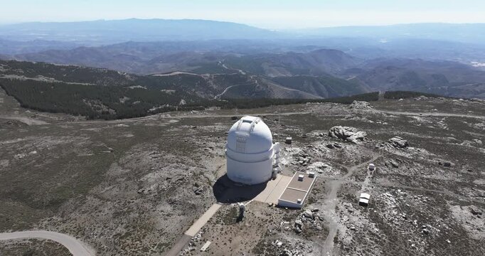 Drone aerial wide shot of Calar Alto Observatory, Tabernas Spain, main dome isolated on rocky plateau with distant mountain horizons