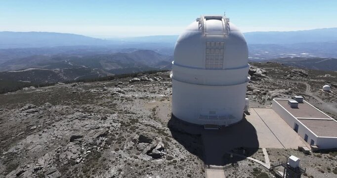 Drone aerial orbit around Calar Alto Observatory dome, Tabernas Spain, astronomy research facility on high plateau with mountains in distance
