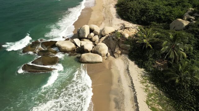 Drone view highlighting dense tropical greenery and hills framing the wild coastline of Tayrona Park.
