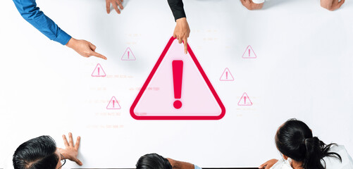 Team Collaboration Concept with Warning Alert Symbol and Group Discussion Over Table in Modern Office Setting Focusing on Risk Assessment and Solutions Trope.