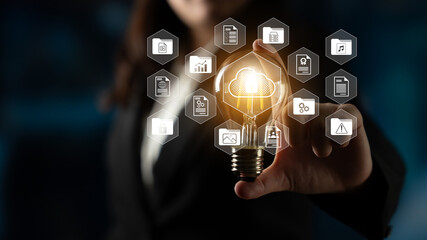 A businesswoman presents a light bulb surrounded by digital icons, symbolizing innovation and technology in a modern office space, reflecting creativity and strategy. Gantry
