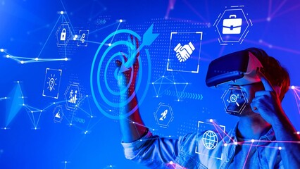 Young man using virtual reality headset to interact with digital interface displaying business icons and technology graphics in futuristic environment Gluon.