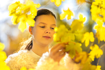 Beautiful young woman with autumn yellow leaves. Portrait of joyful woman playing with tree leaves in park during autumn. Happy girl wearing red turtleneck and headband and playing with leaves outside