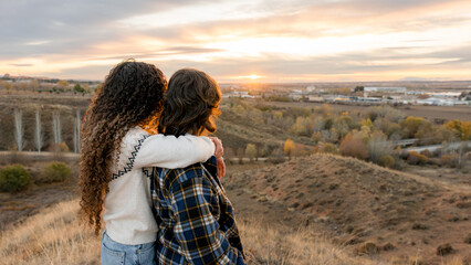 Lesbian couple embracing at sunset in rural area