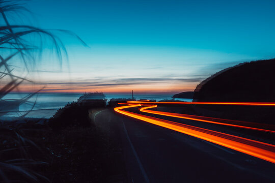 Slow shutter photo of car lights on a coast road