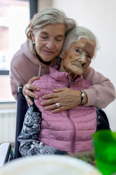 Elderly woman hugged by a family member in a senior residence