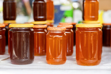Glass jars of fresh honey in various shades on a table
