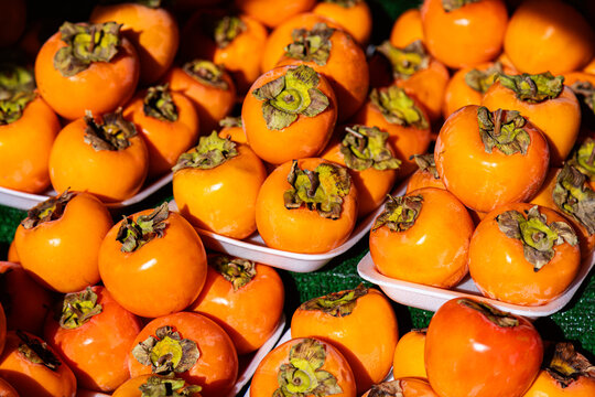 Fresh persimmons stacked in white trays at market