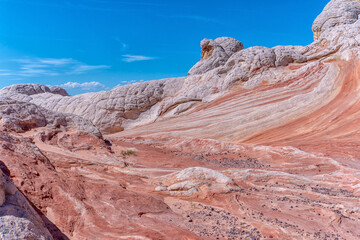 A rocky, barren landscape with a blue sky in the background. The rocks are white and red, and the sky is clear and bright