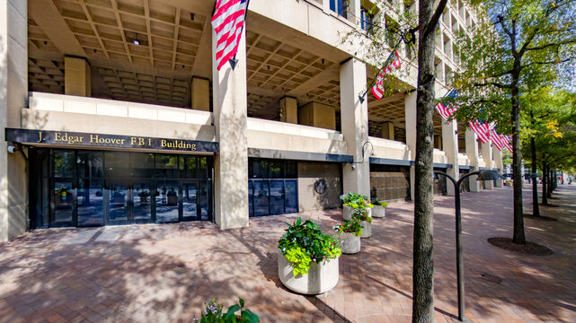 Main FBI headquarters with American flags and concrete plaza in downtown DC