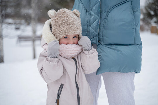 Child bundled up in winter attire beside parent