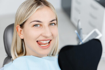 Smiling patient sitting in dentist chair showing perfect teeth