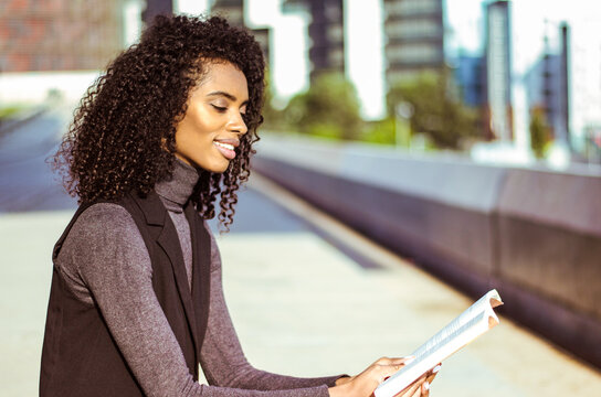Woman reading in urban setting with natural curls