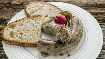 Rice sausage served with bread and pickled vegetables on a wooden table