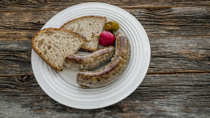 Liver and rice sausage served with bread and pickled vegetables on a white plate