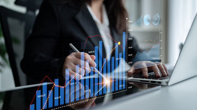 A business analyst focuses on data analysis using graphs and charts while sitting at a laptop in a modern office, showcasing the importance of technology in decision-making. Scalp - Powered by Adobe