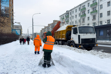 Snowplow picking up snow on city street after heavy snowfall in winter. Weather conditions and city...