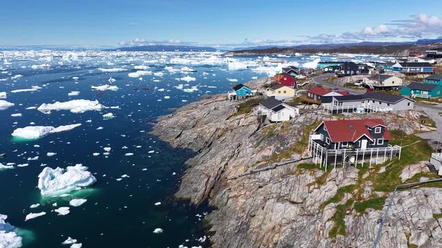 GREENLAND - 11.4.2025 - Amazing aerial footage moving up a colorful coastal Greenland village with ice floes in the water.