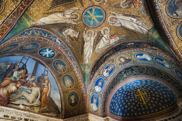 Ravenna, Italy, Ancient Christian vault with gold mosaics of angels, cross, and fresco of Christ's burial in richly decorated interior. © Stefano Pessina