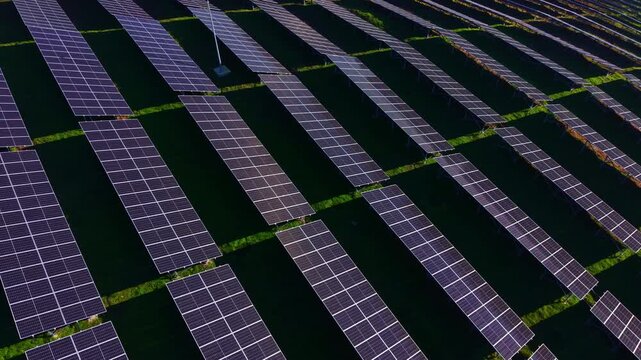 Vast landscape filled with aligned solar panels capturing sunlight to generate clean energy. Green grass peeks through spaces, harmonizing technology and nature in this productive setting.