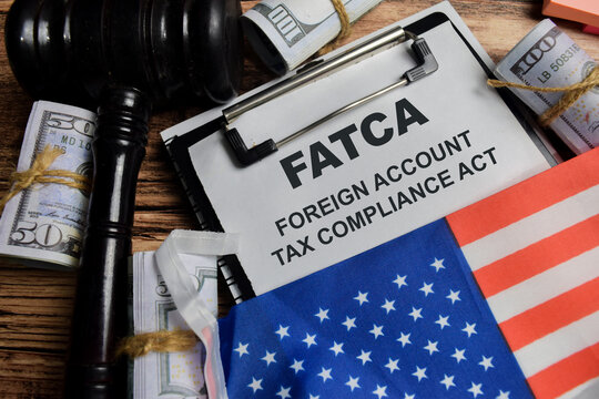 Concept of FATCA - Foreign Account Tax Compliance Act write on clipboard isolated on Wooden Table.
