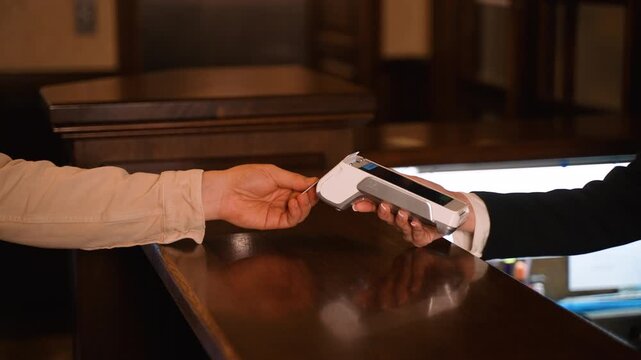 Client using contactless payment at hotel reception desk