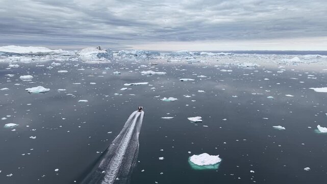 GREENLAND - 11.4.2025 - Beautiful aerial footage following a small speed boat as it navigates ice floes on Greenland's Disko Bay.
