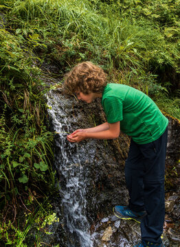A boy drinks fresh water uses his hands from a spring during a hike in Innerdalen Norway. The valley is known for its natural beauty and offers a refreshing experience in the outdoors.
