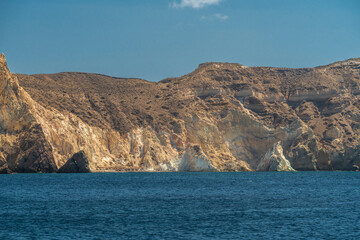 Expansive rocky coastline with layered cliffs above calm blue sea