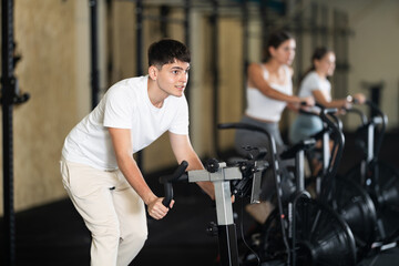 Young guy doing sports on a stationary bike in the gym