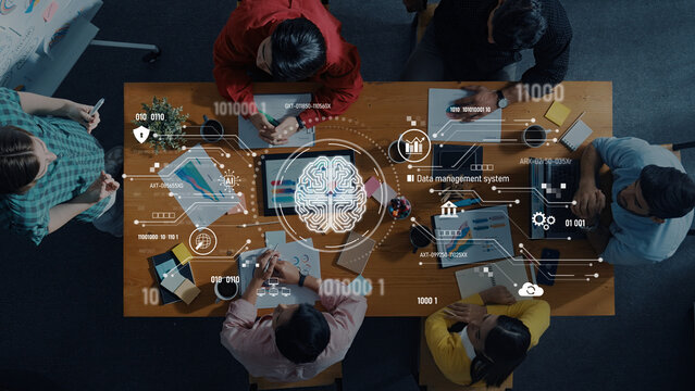 A diverse group of professionals collaborates in a modern workspace, analyzing data management systems and engaging in strategy discussion around a table. Trope - Powered by Adobe