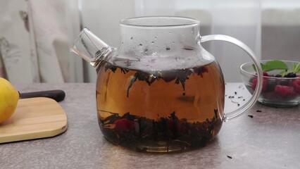 Process brewing tea, tea ceremony, Cup of freshly brewed fruit herbal tea, dark mood. Hot water is...