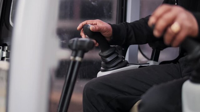 Operator hand controlling joystick inside industrial vehicle cabin