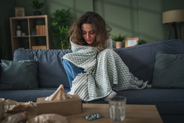 Young woman feeling sick shivering with cold holding a blanket