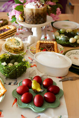 A set and decorated Easter table with festive appetizers, pastries, a baked leg of lamb and painted eggs