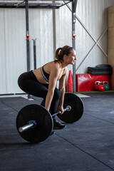 Athletic female doing a barbell squat in the gym