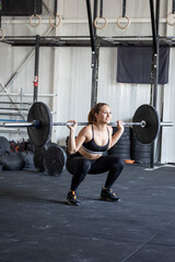 Strong athletic woman performing barbell squat exercise