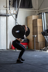 Athletic woman practicing barbell squat technique