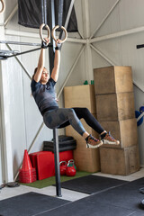 Strong woman exercising on gymnastic rings in an indoor space