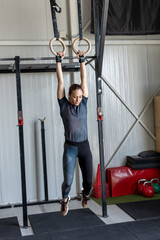 Female athlete working out indoors using gymnastic rings